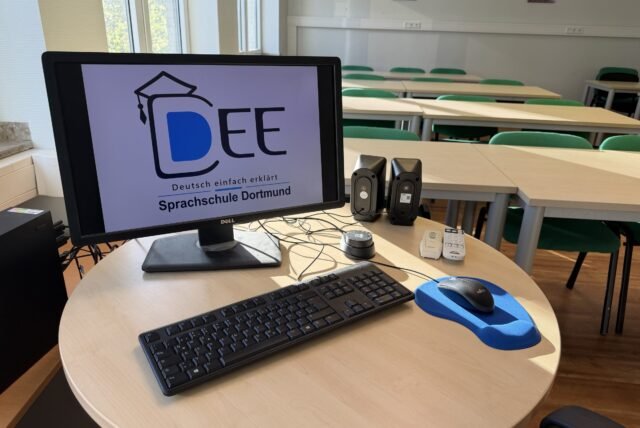 Arbeitsplatz der Lehrkraft mit Bildschirm und DEE-Logo